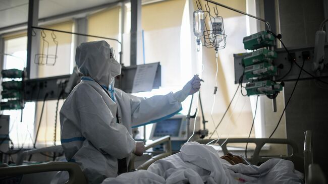 Врач проверяет капельницу у пациента в реанимации городской клинической больницы № 15 имени О. М. Филатова в Москве