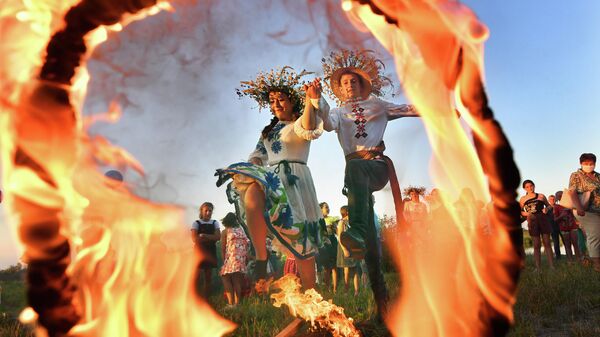 Девушка и юноша прыгают через огонь на празднике Ивана Купалы на берегу залива Припяти в древнем белорусском Турове