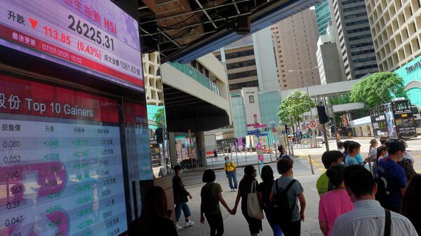 Люди проходят мимо табло с курсом индекса фондовой биржи Гонконга
