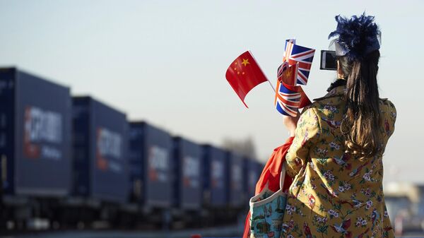 Женщина c флагами Китая и Великобритании фотографирует поезд с товарами из КНР в Лондоне