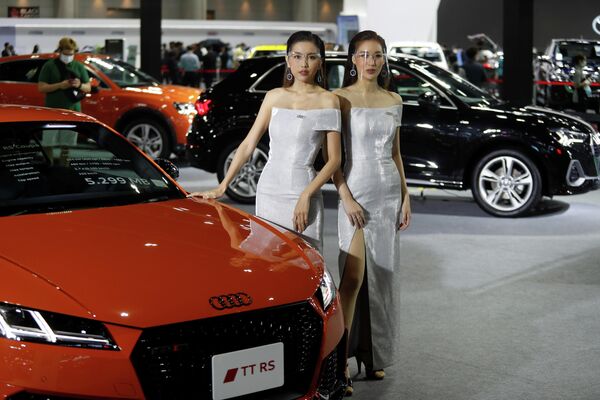 Модели в защитных экранах рядом с автомобилем Audi TT RS Coupe на автошоу в Бангкоке