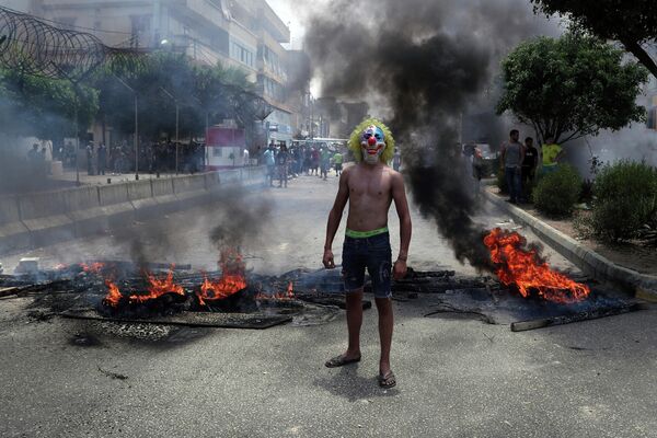 Антиправительственный демонстрант в маске клоуна на заблокированной дороге в Бейруте, Ливан