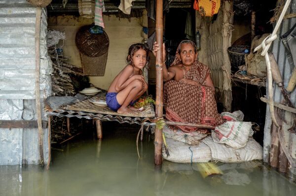 Женщина и девочка в затопленном доме в Сунамгандже