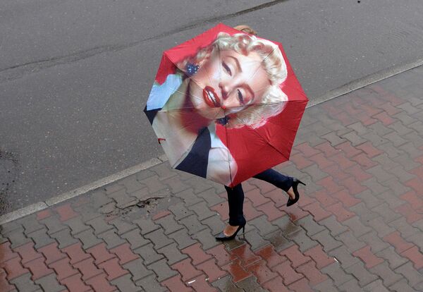 Женщина с зонтом на улице во время ливня в Красноярске