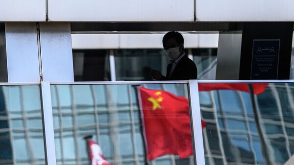 Мужчина на пешеходном мосту, в котором отражается флаг Китая, Гонконг