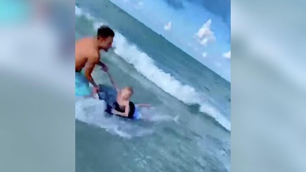 Полицейский Адриан Косицки во время спасения ребенка от акулы во Флориде