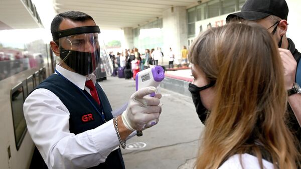 Проводник проверяет температуру у пассажиров на железнодорожном вокзале в Тбилиси