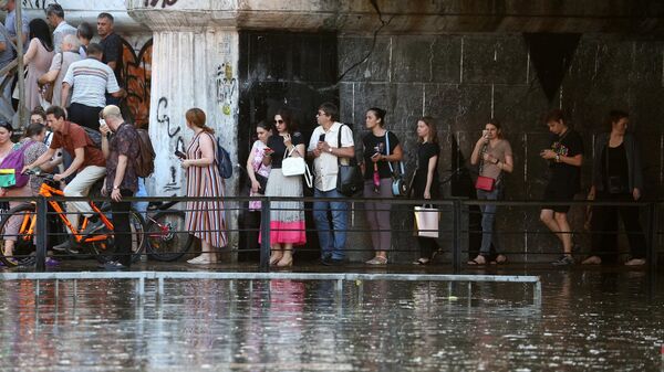 Прохожие на подтопленной после мощного ливня улице Переходной в центре Краснодара