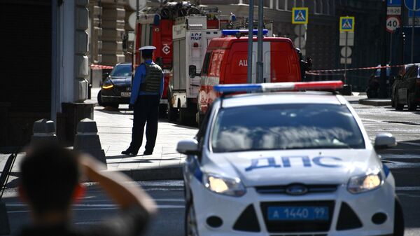 Сотрудник полиции и автомобили экстренных служб недалеко от места обнаружения подозрительного предмета в центре Москвы