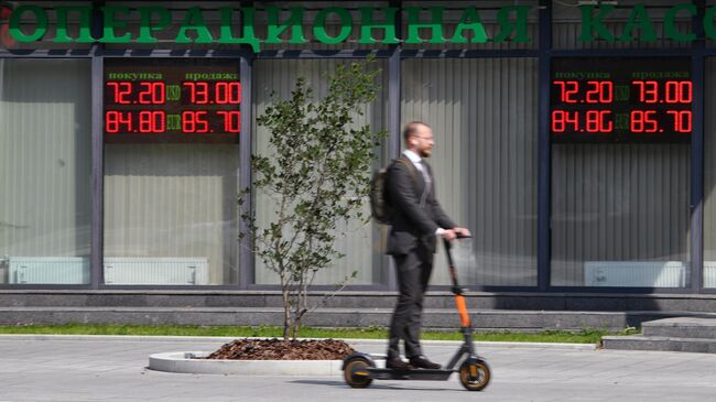 Мужчина около электронного табло с курсами валют в Москве