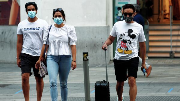 Люди в медицинских масках переходят дорогу в Мадриде, Испания 