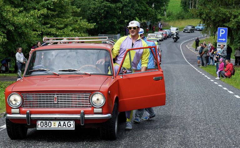 Мужчина садится в автомобиль Lada во время парада по случаю 50-летия марки в городе Вербозе, Эстония