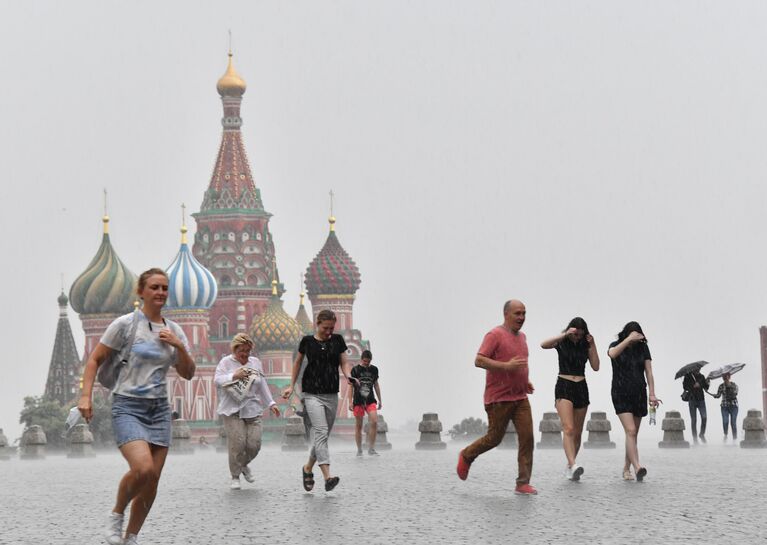 Люди во время дождя на Красной площади в Москве