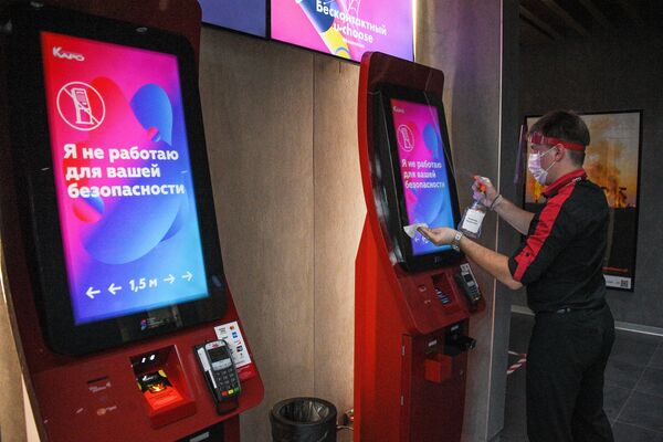 Сотрудник кинотеатра дезинфицирует автомат по продаже билетов перед показом фильма в кинотеатре Каро 11 Октябрь в Москве