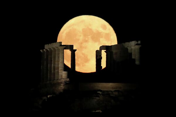 Полная луна за храмом Посейдона на мысе Сунион недалеко от Афин, Греция 