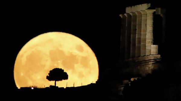 Полная луна за храмом Посейдона на мысе Сунион недалеко от Афин, Греция