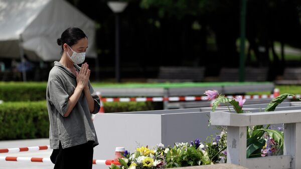 Женщина молится перед кенотафом о жертвах атомной бомбардировки в Хиросиме