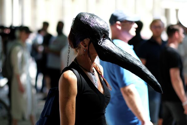 Девушка в маске чумного доктора на демонстрации против ограничений по Covid-19 в Берлине 
