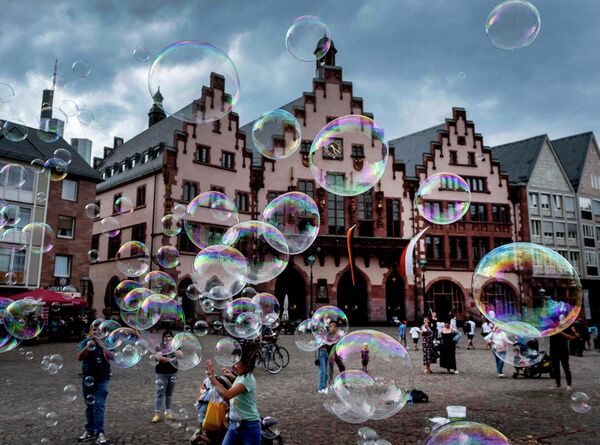 Уличный артист пускает мыльные пузыри перед зданием ратуши во Франкфурте, Германия