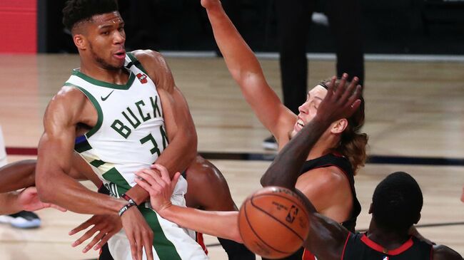 LAKE BUENA VISTA, FLORIDA - AUGUST 06: Giannis Antetokounmpo #34 of the Milwaukee Bucks passes the ball against Kelly Olynyk #9 and Kendrick Nunn #25 of the Miami Heat during the second half at The Arena at ESPN Wide World Of Sports Complex on August 6, 2020 in Lake Buena Vista, Florida. NOTE TO USER: User expressly acknowledges and agrees that, by downloading and or using this photograph, User is consenting to the terms and conditions of the Getty Images License Agreement.   Kim Klement-Pool/Getty Images/AFP