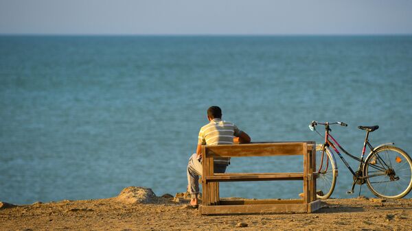 Мужчина отдыхает на пляже в поселке Бузовна в Азербайджане