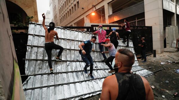 Люди преодолевают полицейский барьер во время протеста в Бейруте, Ливан. 9 августа 2020