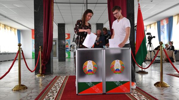 Молодые люди голосуют на выборах президента Белоруссии на избирательном участке в Минске