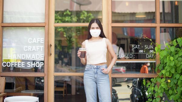 Девушка в защитной маске выходит из кафе 