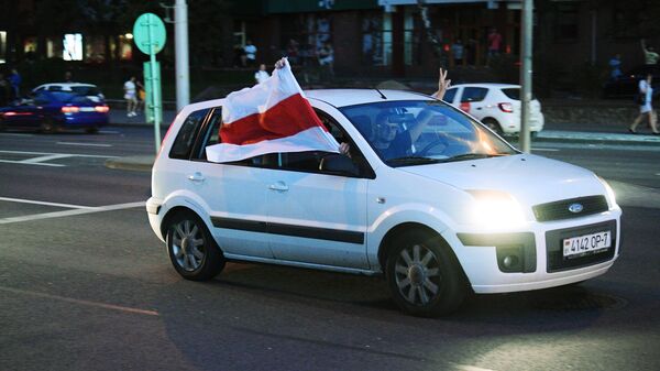 Автомобиль с флагом Республики Беларусь (образца 1991-1995 годов) едет по улице Минска во время акции протеста после президентских выборов