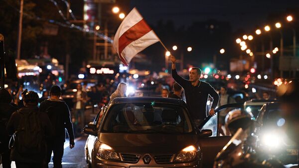 Автомобиль с флагом Республики Беларусь едет по улице Минска во время акции протеста после президентских выборов