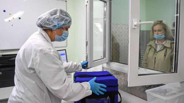 Лаборант принимает термосумку с биоматериалом в лабораторном комплексе Helix в Москве
