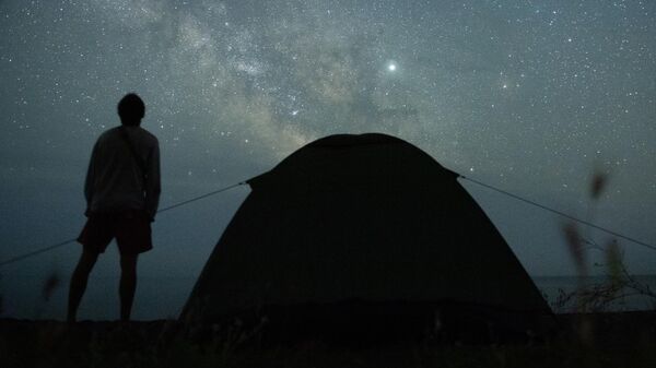 Мужчина наблюдает за звездным небом на берегу Черного моря возле поселка Морское в Крыму