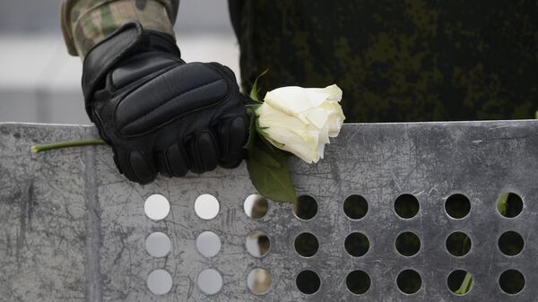 Цветок в руке военнослужащего на акции протеста в Минск