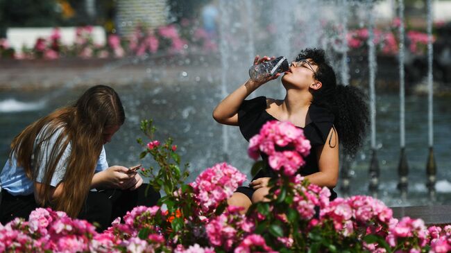 Люди отдыхают у фонтана в жаркий день на территории парка ВДНХ в Москве