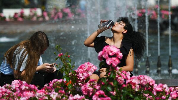 Люди отдыхают у фонтана в жаркий день на территории парка ВДНХ в Москве