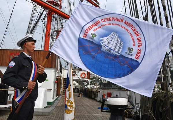 Курсант с флагом экспедиции на борту барка Седов перед отправлением по Северному морскому пути из Владивостока в Калининград