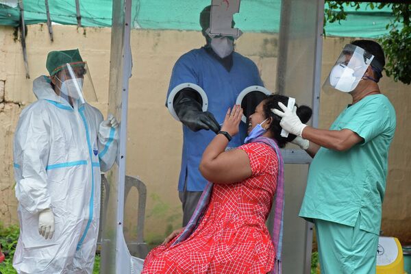 Медицинские работники берут мазок на коронавирус у женщины в Хайдарабаде