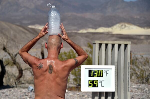 Мужчина с бутылкой льда на голове во время жары в Долине Смерти, Калифорния, США