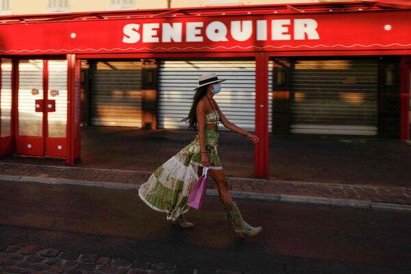 Женщина в защитной маске идет мимо закрытого кафе Le Cafe Senequier в Сен-Тропе