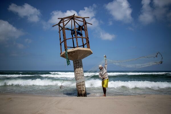 Палестинский рыбак чистит рыболовную сеть после решения Израиля закрыть рыболовную зону в Газе