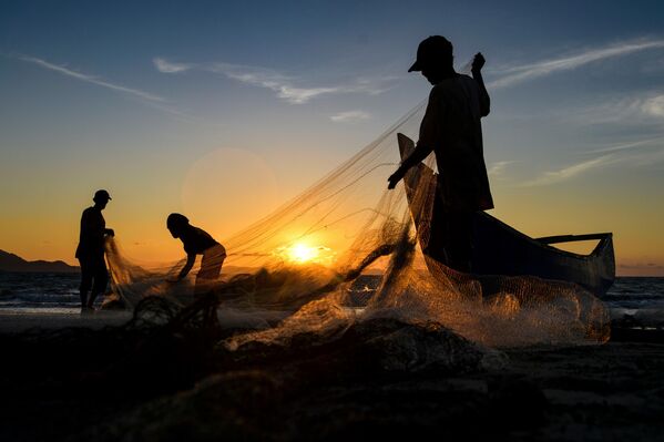 Рыбаки очищают сети после рыбалки в Банда-Ачех