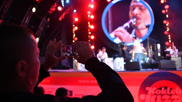 Зритель фотографирует выступление музыкантов на открытии Международного музыкального фестиваля Koktebel Jazz Party в Крыму
