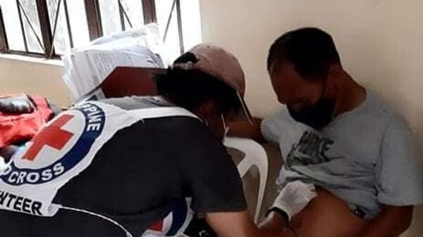 Волонтер Филиппинского красного креста оказывает помощь мужчине пострадавшему при взрыве в городе Холо