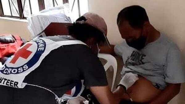 Волонтер Филиппинского красного креста оказывает помощь мужчине пострадавшему при взрыве в городе Холо