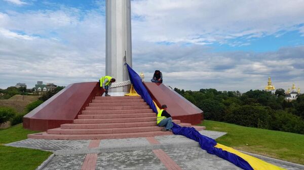 Сотрудники коммунальных служб снимают самый большой флаг Украины в Киеве