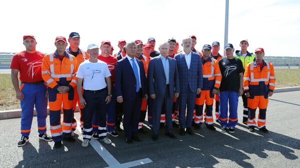 Президент РФ Владимир Путин с рабочими, которые принимали участие в строительстве, на церемонии запуска движения по трассе Таврида в Крыму
