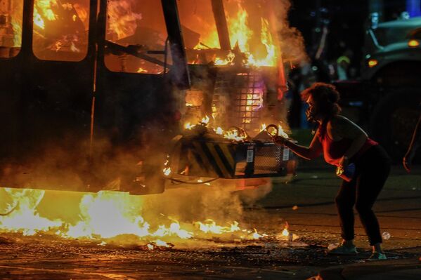 Протестующий возле горящего мусоровоза во время протестов в Кеноша, штат Висконсин