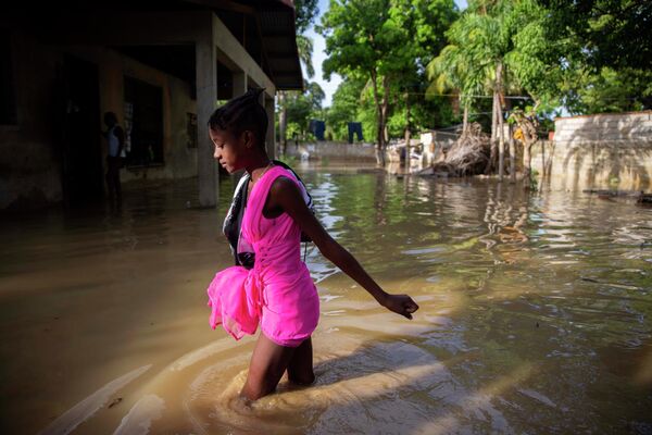 Девушка идет по затопленной улице после урагана Лаура в Порт-о-Пренсе, Гаити
