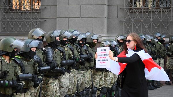 Участница акции протеста и сотрудники правоохранительных органов на проспекте Независимости в Минске