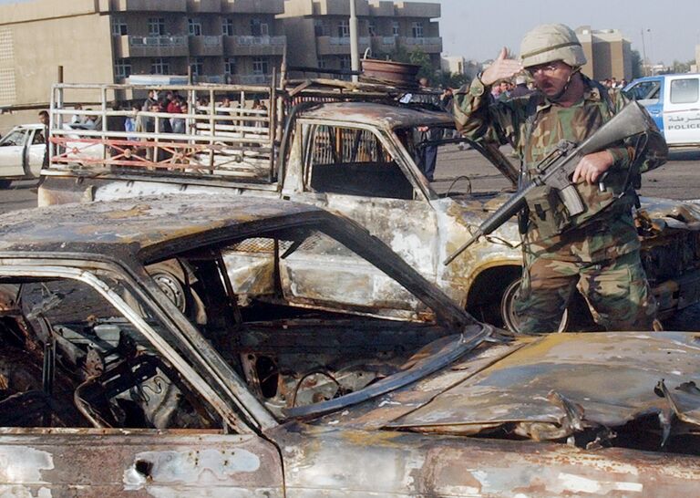 Солдат США осматривает сгоревшие, в результате взрыва, автомобили в Багдаде Солдат США осматривает сгоревшие, в результате взрыва, автомобили в Багдаде